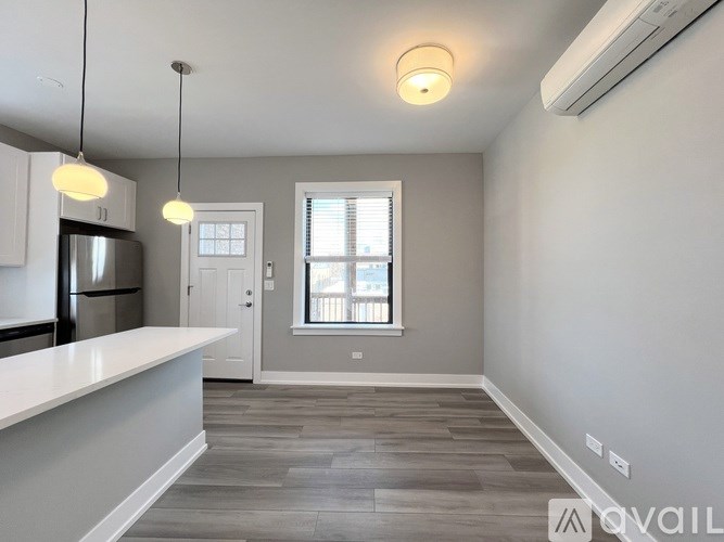 A spacious kitchen and living room with a large window and hardwood floors.