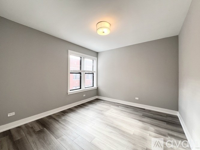 A room with a window and wooden flooring.