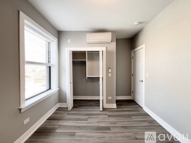 A room with a window, a door, and a wall-mounted air conditioner.