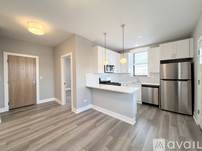 A modern kitchen with a stainless steel refrigerator and wooden flooring.