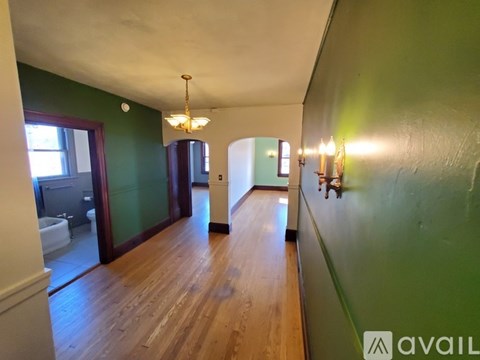 A long hallway with green walls and wood floors.