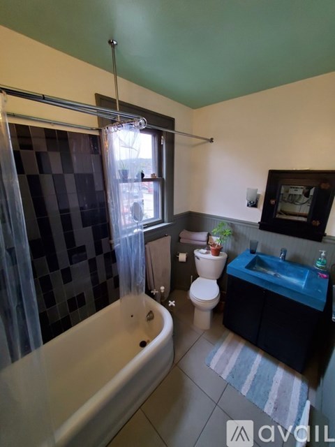 A bathroom with a blue tub and a window with a curtain.