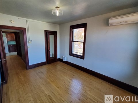 A room with wooden floors and a window with a view of trees outside.