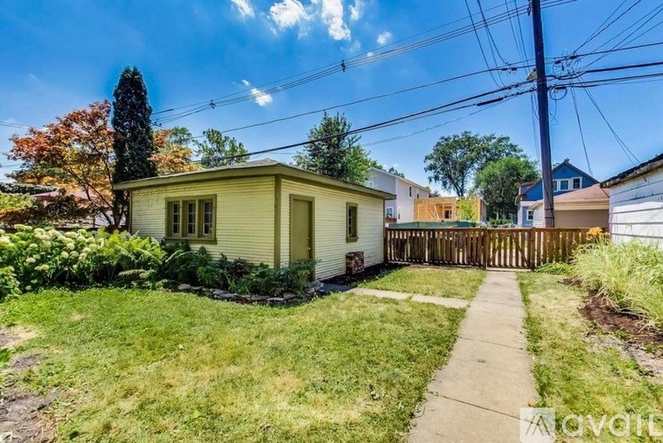 A small house with a fence and a tree in front of it.