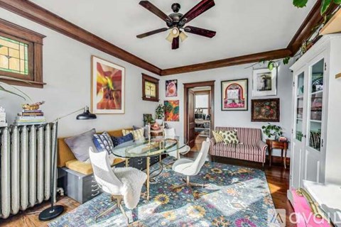 A living room with a glass table and chairs, a sofa, and a ceiling fan.