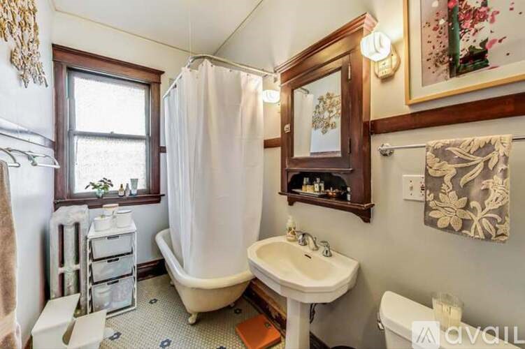 A bathroom with a white sink, a bathtub with a shower curtain, and a window.