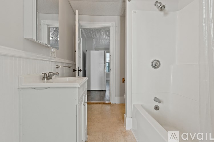 A white bathroom with a sink, mirror, and bathtub.
