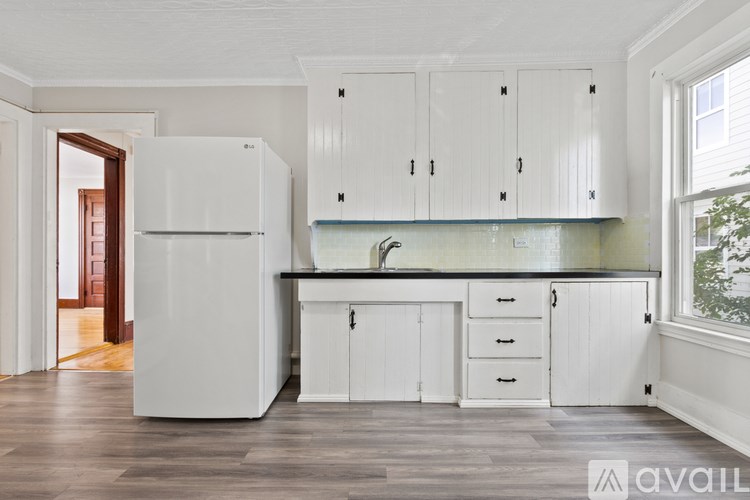 A kitchen with white cabinets and a white fridge.