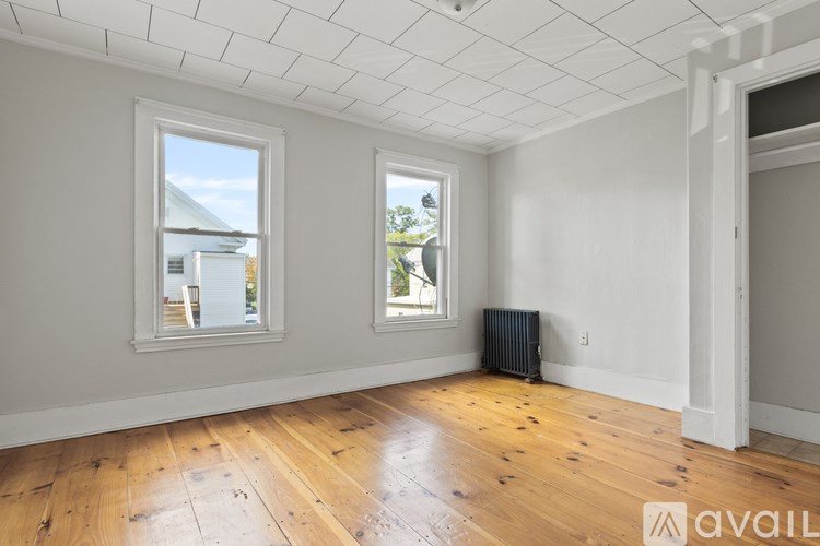 A room with wooden floors and two windows.