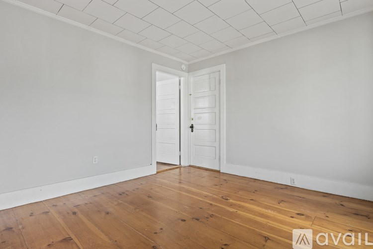 A room with a white door and wooden flooring.