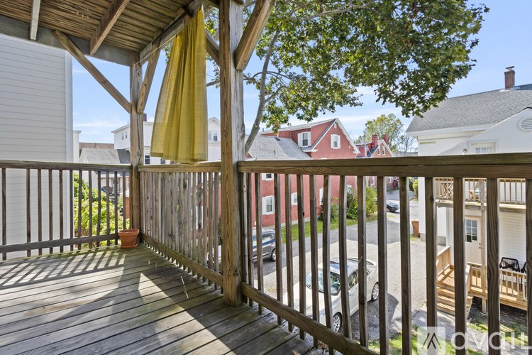 A balcony with a yellow umbrella and a view of a street.