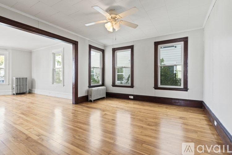 A spacious room with wooden floors and a ceiling fan.