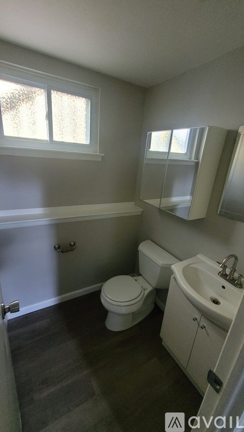A bathroom with a toilet, sink, and window.