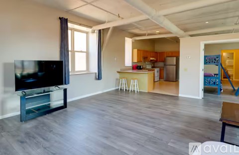A living room with a television and a kitchen in the background.