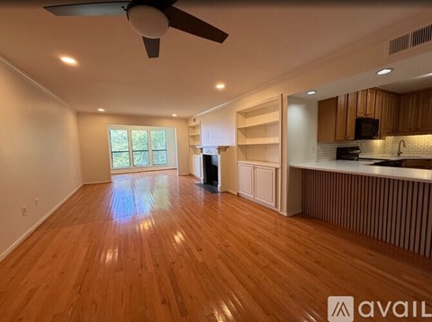 A spacious room with wooden flooring and a ceiling fan.