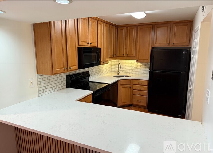 A kitchen with wooden cabinets and black appliances.