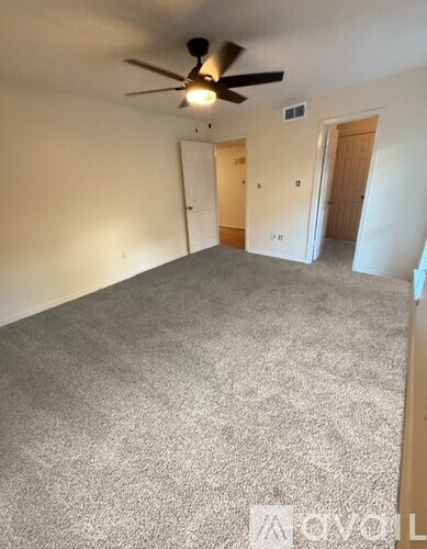 A room with a ceiling fan and carpeted floor.