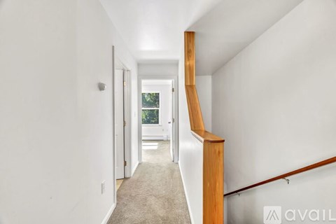 A hallway with a carpeted floor and a wooden staircase.