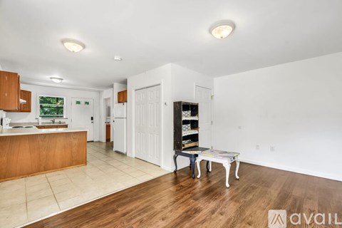 A kitchen with white walls and wooden floors is available for rent.