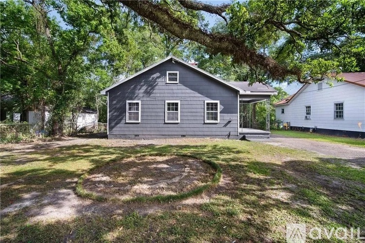 A grey house with a white one in the background.
