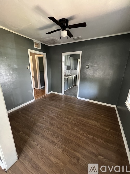 A room with a ceiling fan and wooden flooring.