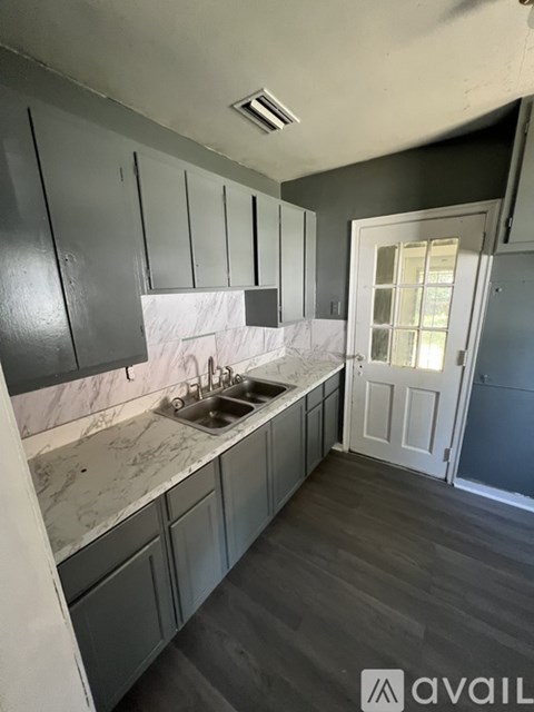 A kitchen with grey cabinets and marble countertops.