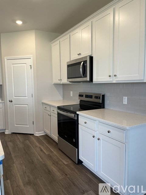 A kitchen with white cabinets and a black microwave.