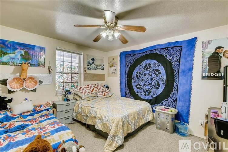 A bedroom with a bed, a ceiling fan, and a wall hanging.