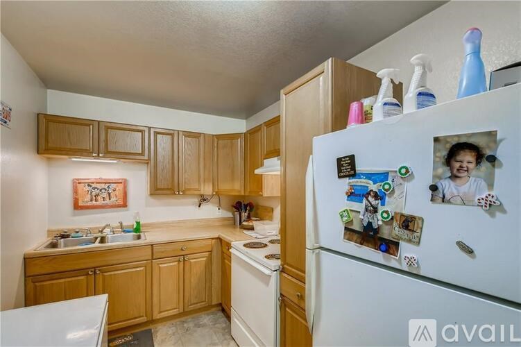 A kitchen with wooden cabinets and a white fridge covered in magnets.