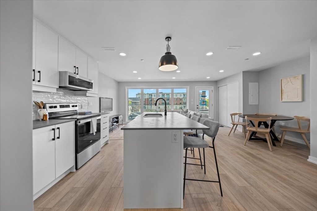 A modern kitchen with a large island and wooden flooring.