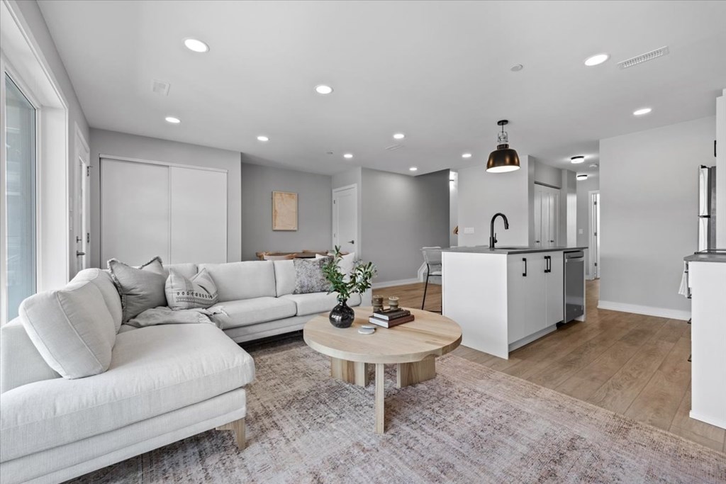 A modern living room with a white sofa and a wooden coffee table.
