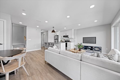 A modern living room with a white couch and a wooden dining table.