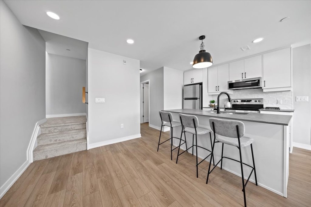 A kitchen with white cabinets and a bar area with four chairs.