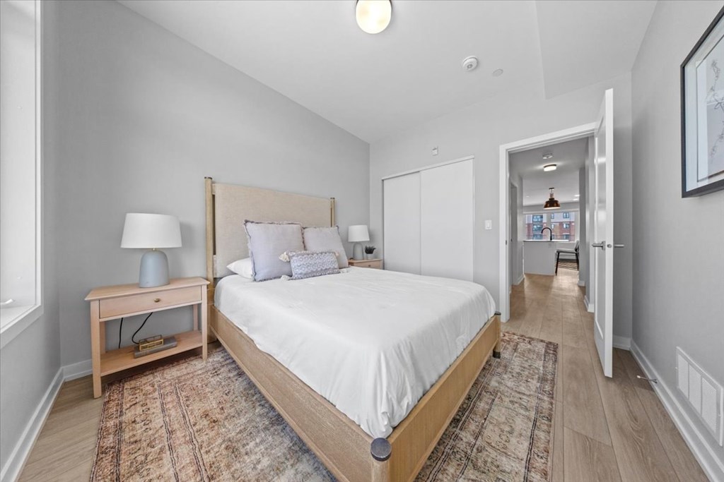 A bedroom with a large bed and a lamp on a side table.