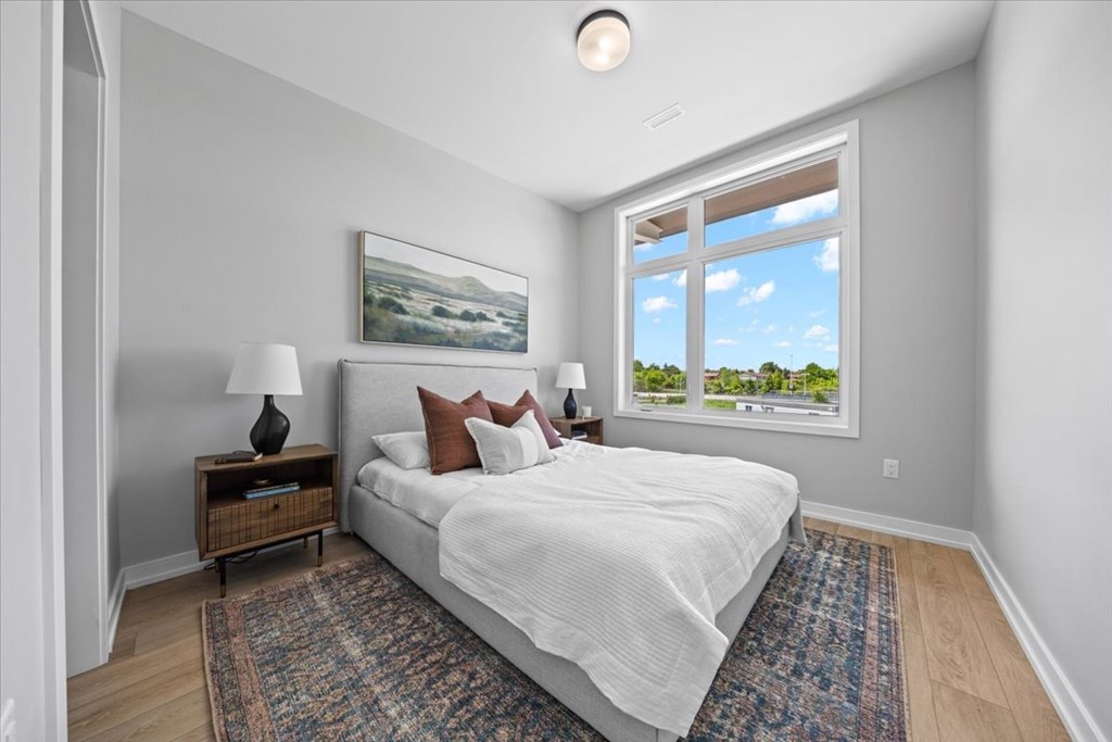 A bedroom with a large bed, a nightstand with a lamp, and a painting on the wall.