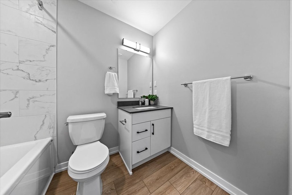 A white toilet sits in a bathroom next to a bathtub.