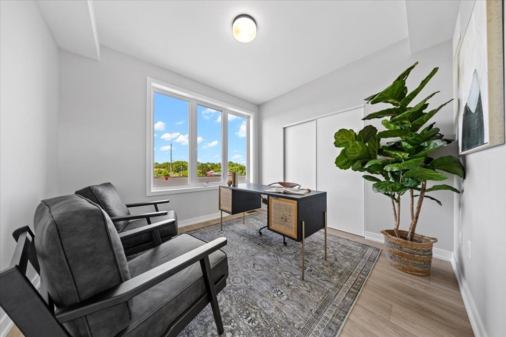 A living room with a black chair and a table with a plant on it.