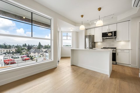 A kitchen with white cabinets and a large window overlooking a street.
