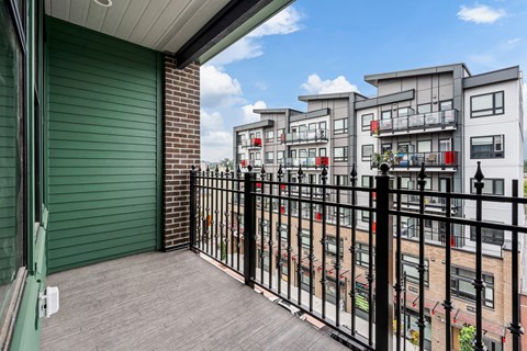 A balcony with a black railing and a green door.