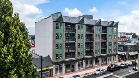 A modern building with green trim is situated on a street corner.