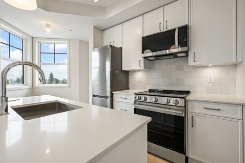 A modern kitchen with white cabinets and stainless steel appliances.