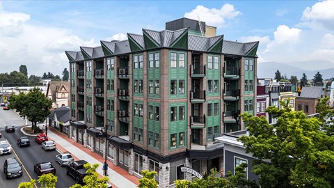 A large green building with a black roof sits on a street corner.