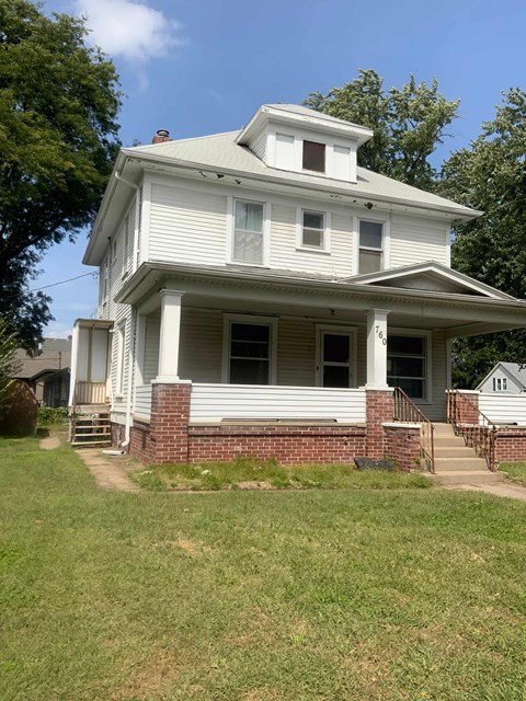 A white house with a porch and a covered staircase.