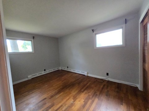A room with wooden floors and two windows.