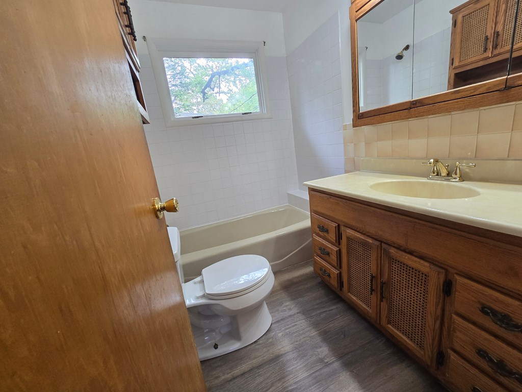 A bathroom with a toilet, sink, and mirror.