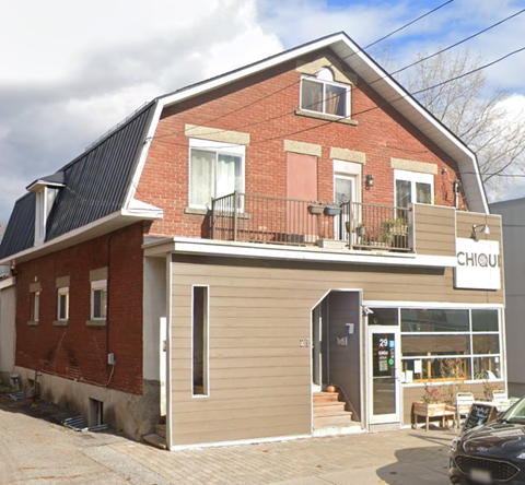 A red brick building with a black metal roof and a sign that says "CHIQU".