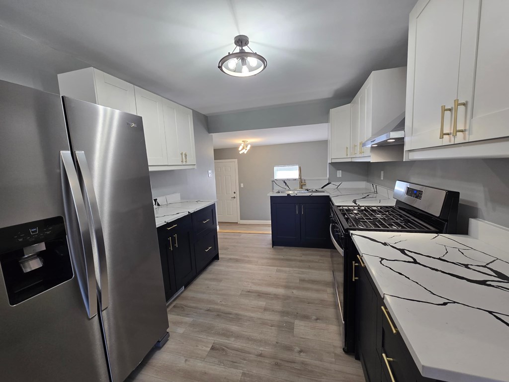 A kitchen with a refrigerator, cabinets, and a laptop on the counter.
