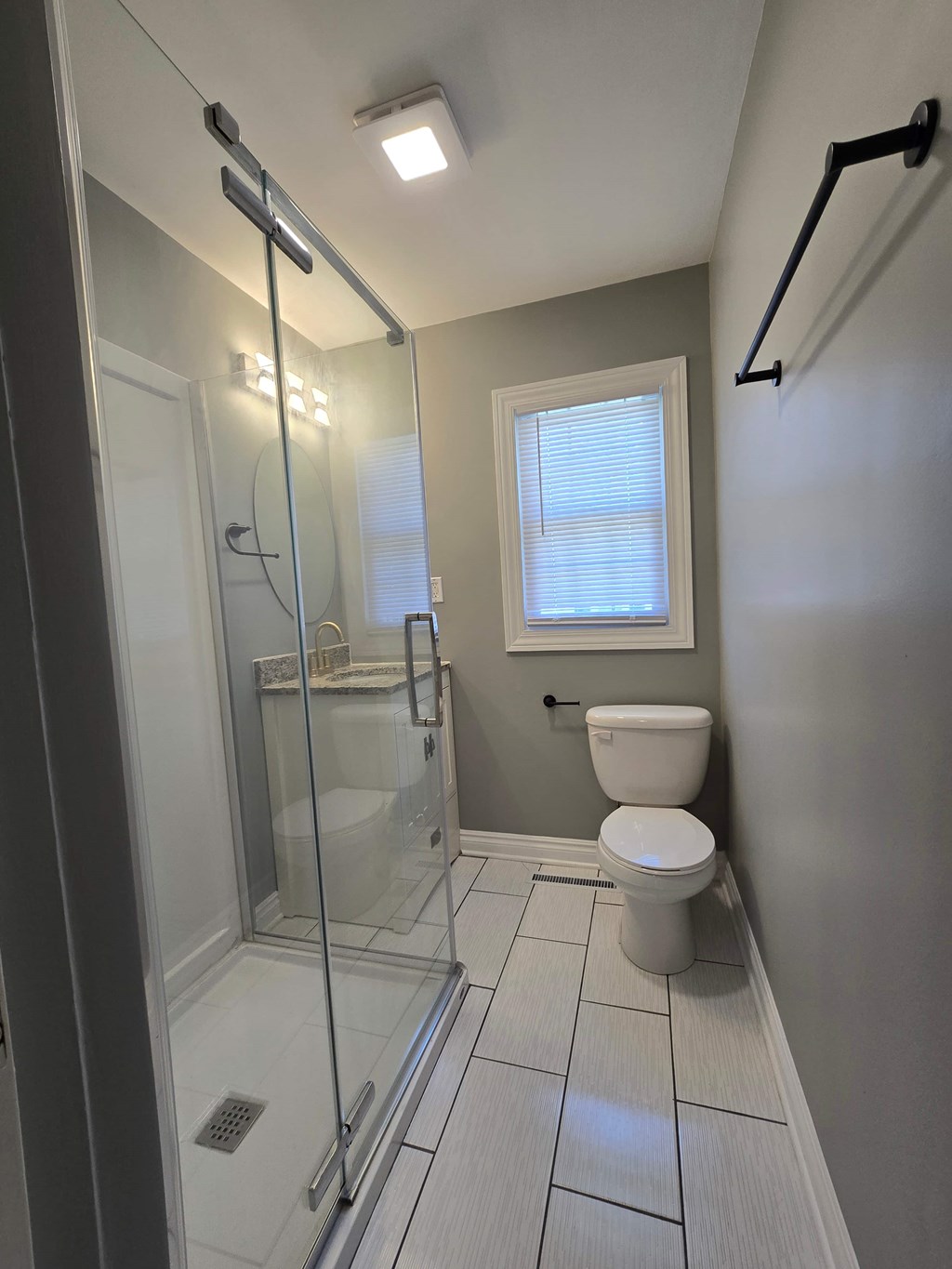A white toilet sits next to a walk-in shower in a bathroom.