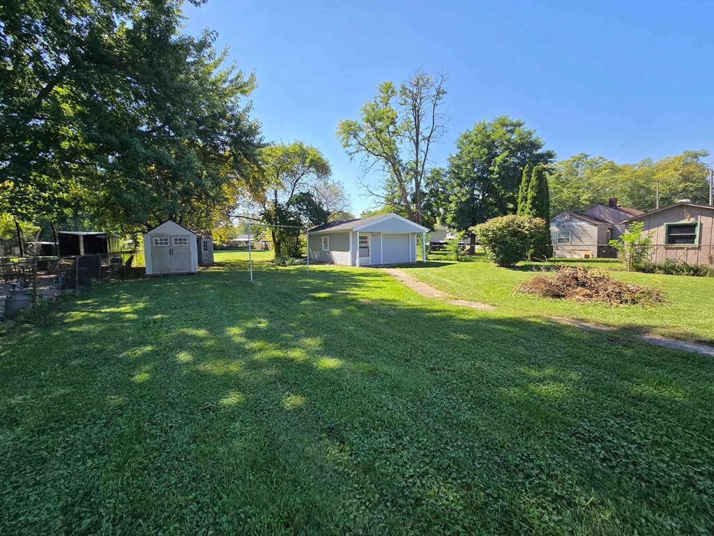 A backyard with a green lawn and a shed.