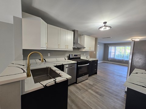 A kitchen with white cabinets and a black countertop.